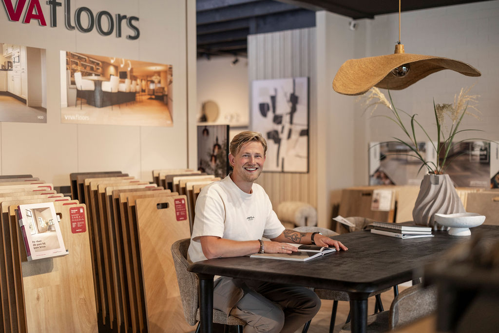 Adviseur aan tafel in de showroom, met vloerpanelen om kleuren en materialen te vergelijken